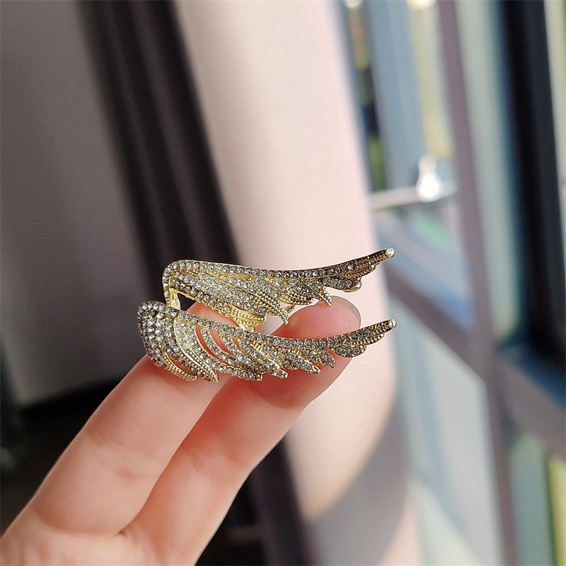 Close-up of vintage angel wings brooch on fabric