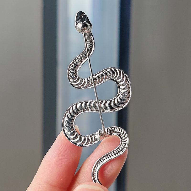 Gold snake brooch on white fabric